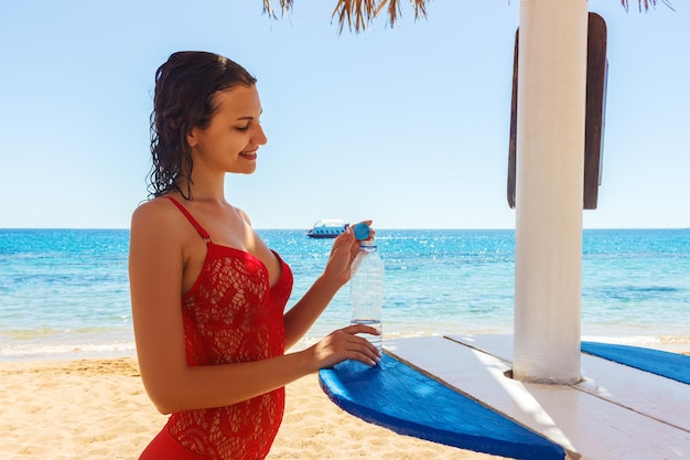 ビーチで水を保持している幸せな若い女性 Premium写真