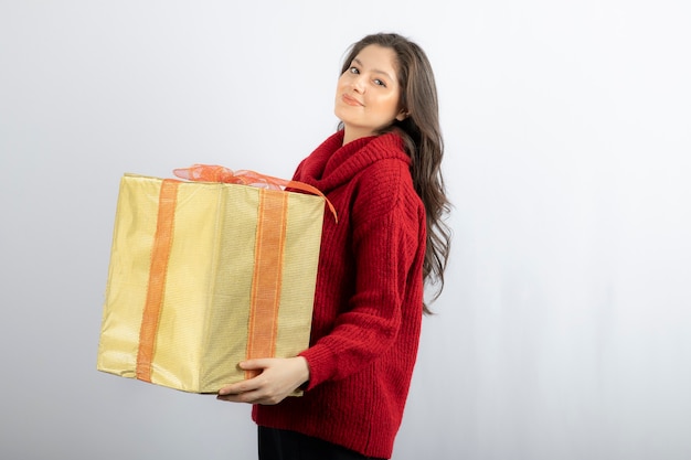Happy young woman holding Christmas present box . 