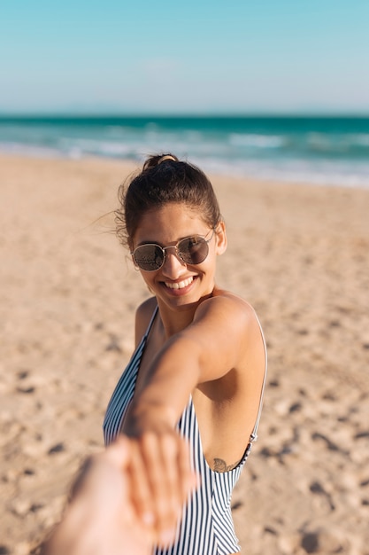Happy young woman holding hand on seashore