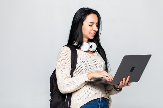 Happy young woman holding laptop and  over gray wall