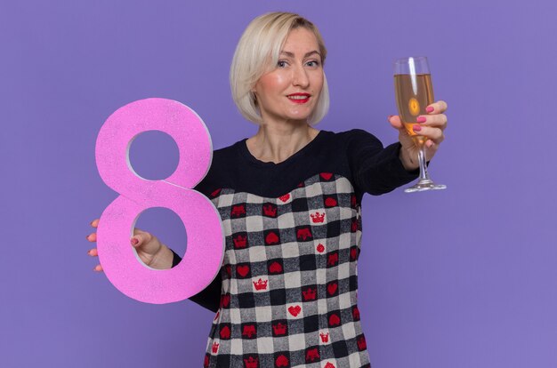 Foto gratuita felice giovane donna azienda numero otto e un bicchiere di champagne