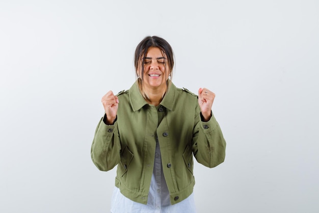 The happy young woman is raising up her fists on white background