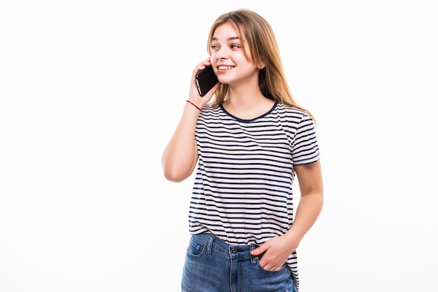 Happy young woman is talking by phone on white wall.