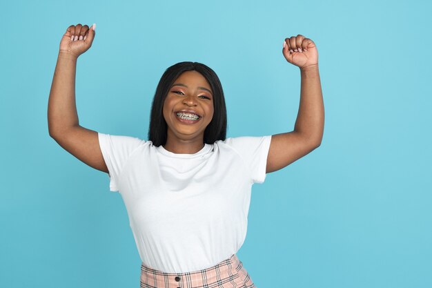 Happy young woman isolated on blue studio wall