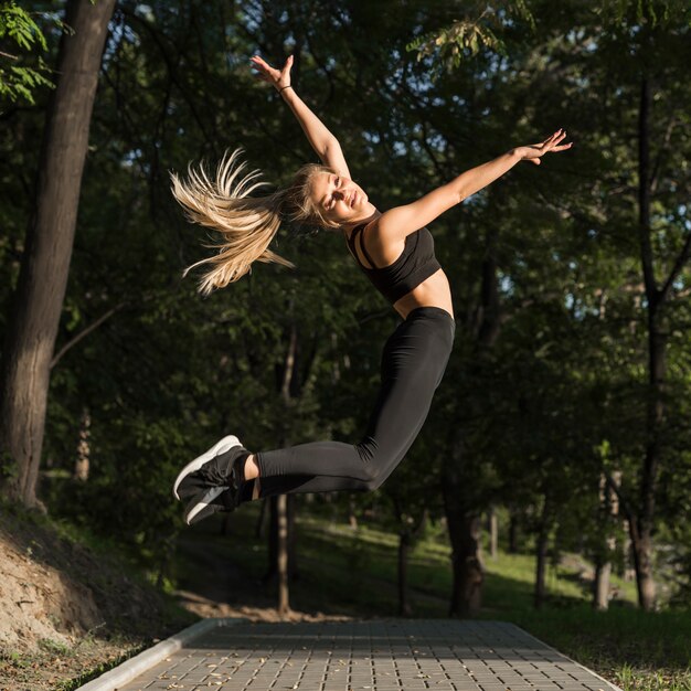 Happy young woman jumping in the park