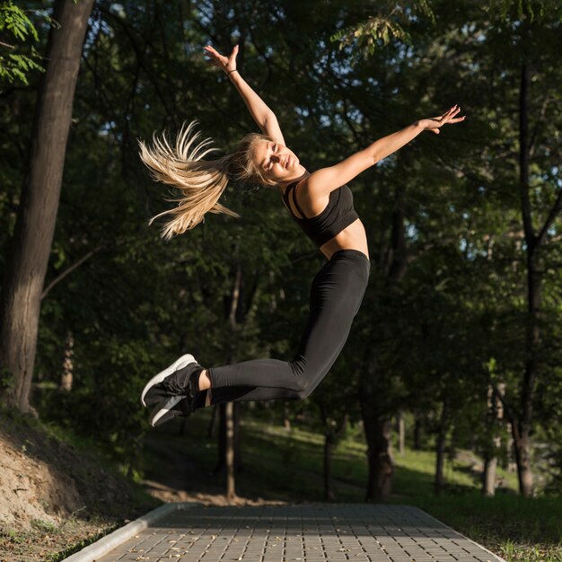 행복 한 젊은 여자는 공원에서 점프