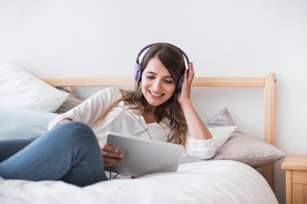 Happy young woman listening music on the bed