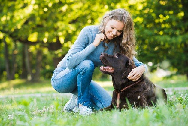 公園で彼女の犬を見ている幸せな若い女性