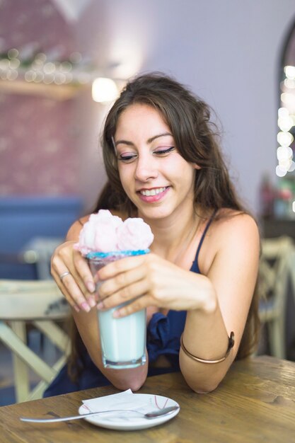 レストランに座ってアイスクリームのガラスを見て、幸せな若い女性