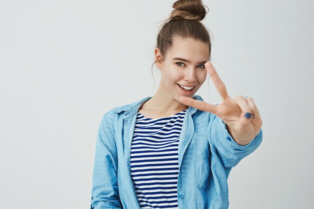 Happy young woman making victory gesture with fingers, V sign