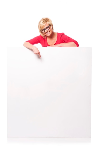 Happy young woman pointing at billboard