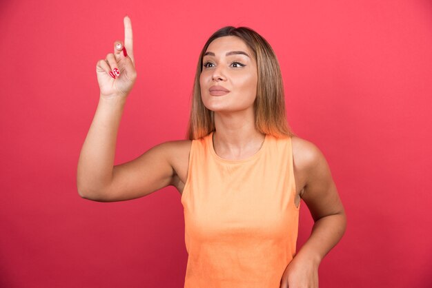 Happy young woman pointing her finger up.