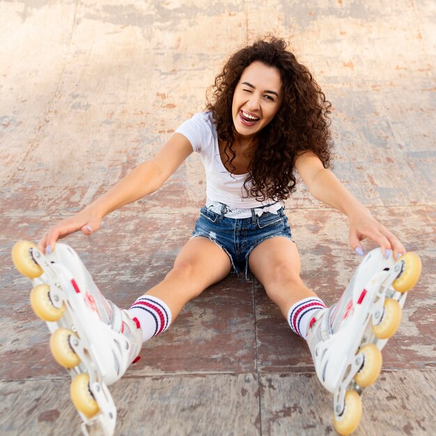 Happy young woman posing outdoors with rollerblades