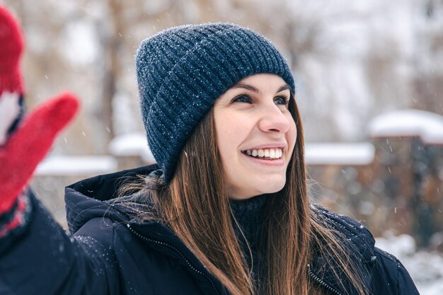 雪の降る天気でカナダの旗と赤いミトンで幸せな若い女性