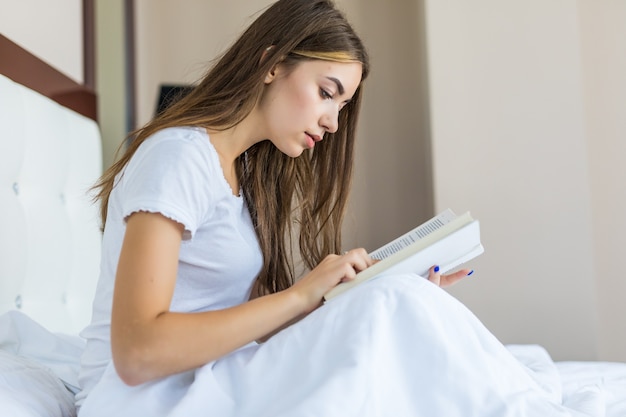 Free photo happy young woman relaxing at home and reading a book