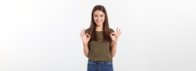 Happy young woman showing ok sign with fingers an winking isolated on a gray background