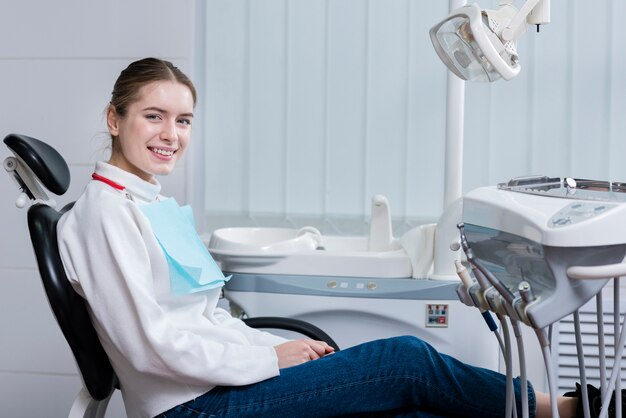 Счастливая молодая женщина улыбается у стоматолога