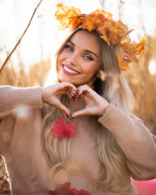 Happy young woman smiling and making heart shape with hand at outdoors