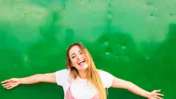 Free photo happy young woman standing in front of green background