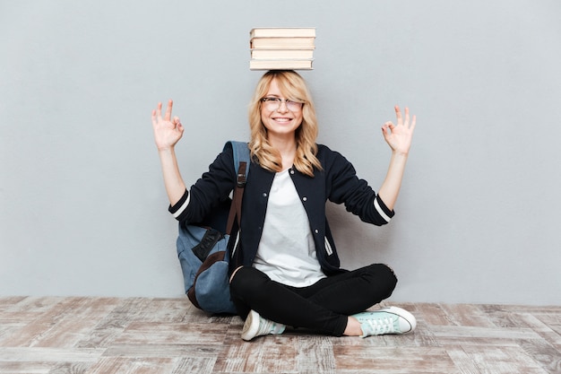 Free photo happy young woman student holding books on head.