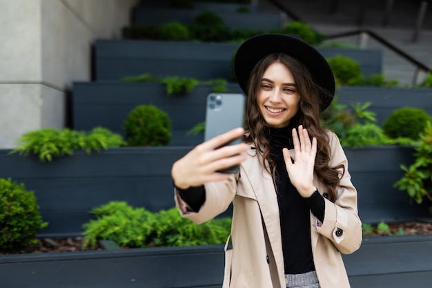 Happy young woman taking selfie with peace sign on city street