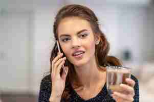 無料写真 自宅でスマートフォンで話している幸せな若い女性。屋内で電話をかける魅力的な女性。