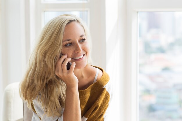 행복 한 젊은 여자 집에서 휴대 전화 통화