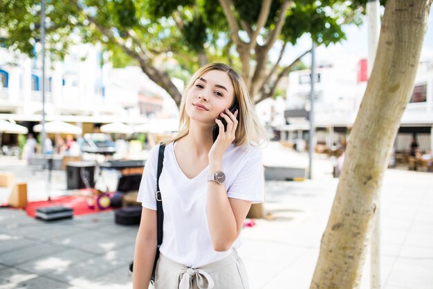 Счастливая молодая женщина разговаривает по телефону на портрете городской уличной жизни в летнее время