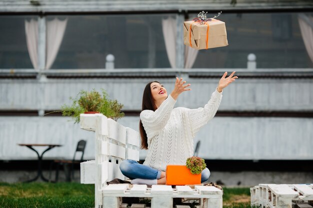 空気に贈り物を投げ幸せ若い女性