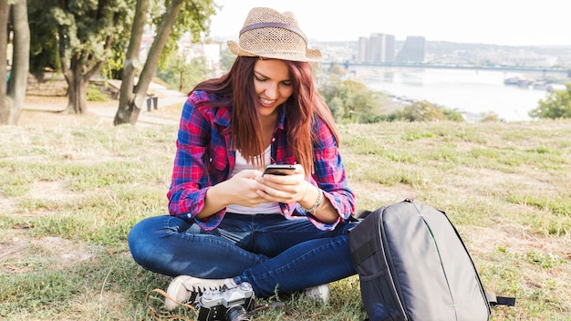 Happy young woman using cellphone in park