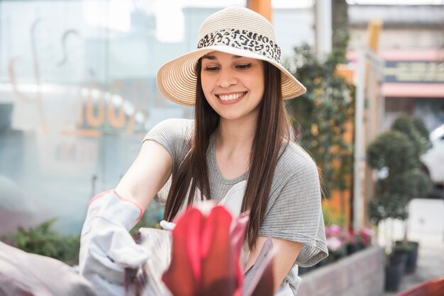 Happy young woman wearing hat taking car of plant