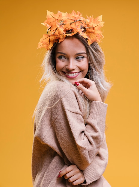 Happy young woman wearing tiara and posing against yellow wall