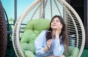 Happy young woman with chocolate ice cream in a hammock