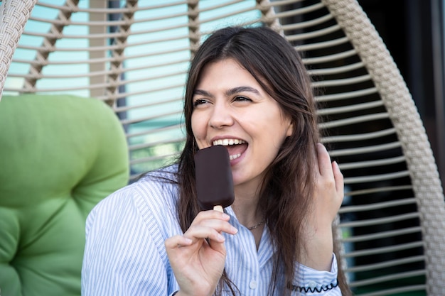 Бесплатное фото Счастливая молодая женщина с шоколадным мороженым в гамаке