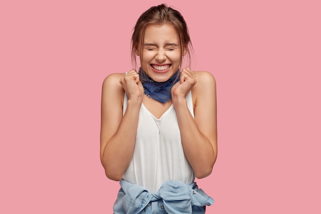 Happy young woman with glasses posing against the pink wall