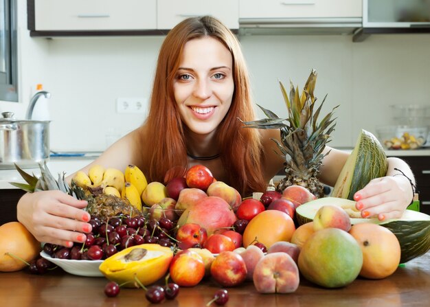 Happy young woman with heap of fruits