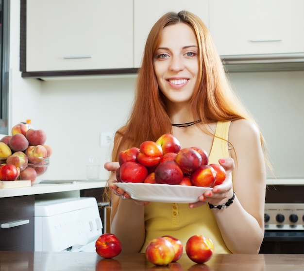 Happy young woman with nectarines