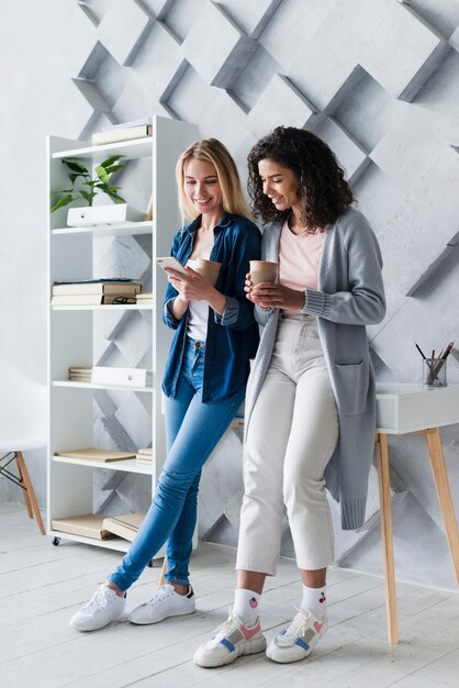 Happy young women drinking coffee in office