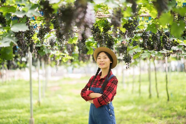 잘 익은 푸른 포도의 가지를 들고 행복 한 젊은 여성의 정원사