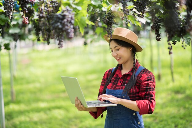Счастливый садовник молодых женщин держа ветви зрелого голубого винограда