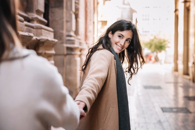 Happy young women holding hands on street