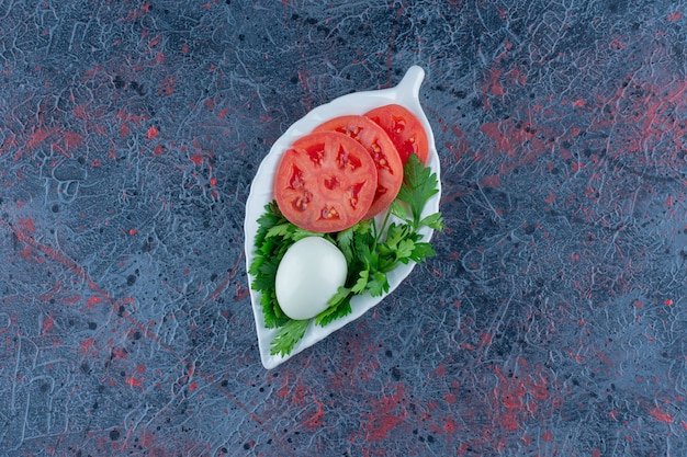 Foto gratuita uovo sodo con pomodoro a fette ed erbe aromatiche.