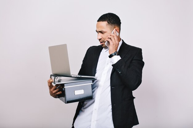 Трудолюбивый удивленный бизнесмен с офисной коробкой, папками, ноутбуком разговаривает по телефону. Офисный работник, карьера, умный менеджер, непонимание, лидерство.