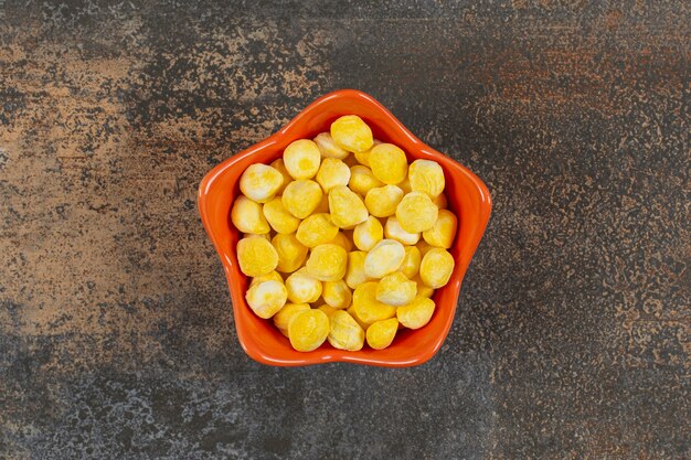 Твердые желтые конфеты в оранжевой миске.