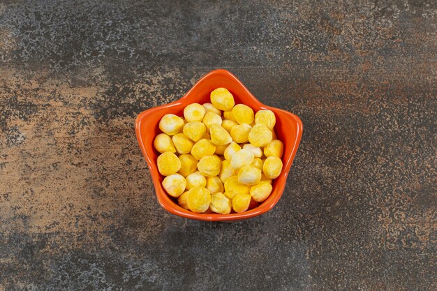 Hard yellow candies in orange bowl.
