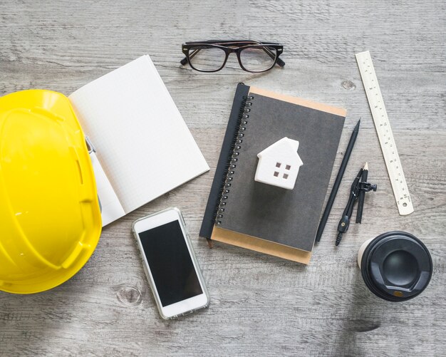 Hardhat and stationery near smartphone and cup