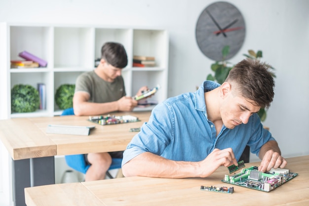 Foto gratuita studenti del tecnico dell'hardware che si esercitano con le componenti del computer