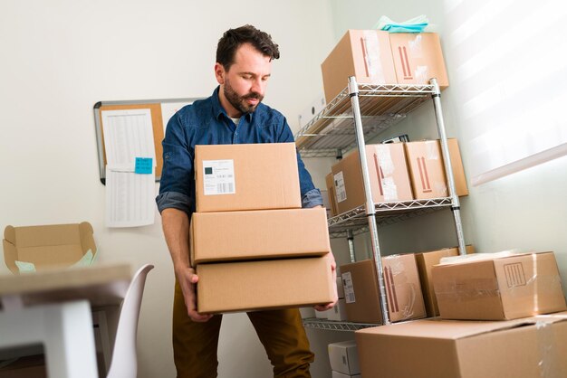 Hardworking business owner with a growing online business shop. Attractive entrepreneur arranging the packages in his small office