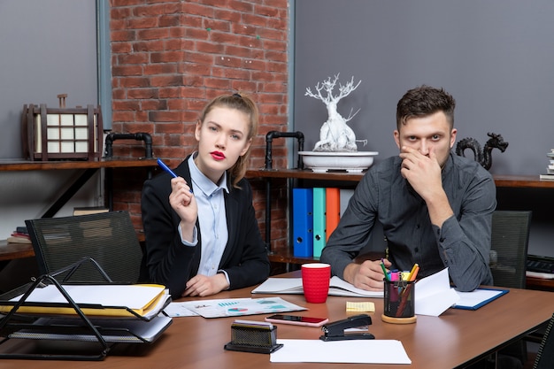 Трудолюбивая и сбитая с толку команда менеджеров обсуждает один вопрос в документах в офисе