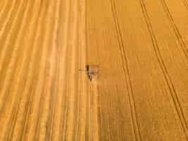 Foto gratuita macchina per la raccolta che lavora sul campo vista dall'alto dal drone macchina agricola per mietitrebbia in giro sul campo